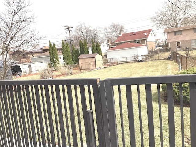 view of yard featuring an outbuilding, a fenced backyard, a storage shed, and a residential view