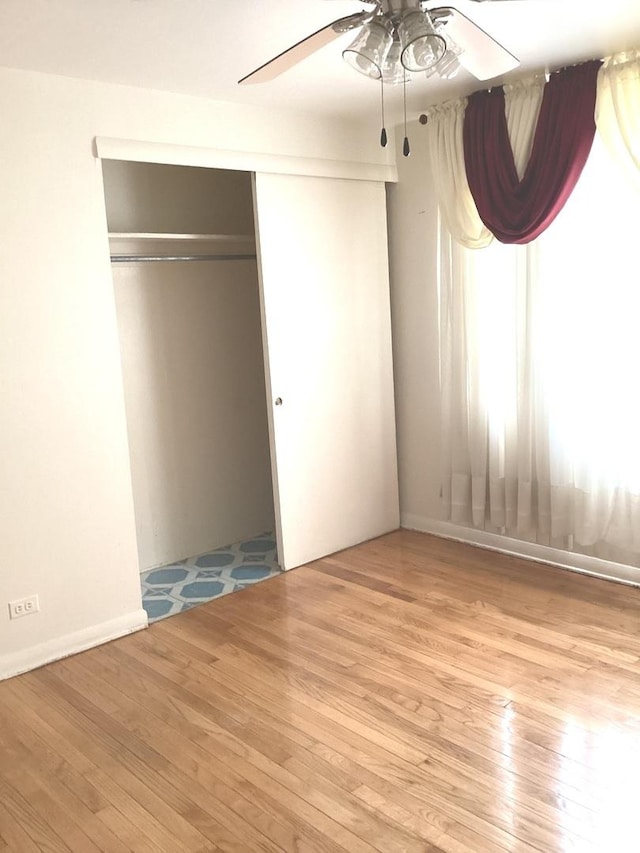 unfurnished bedroom featuring a closet, wood finished floors, and a ceiling fan