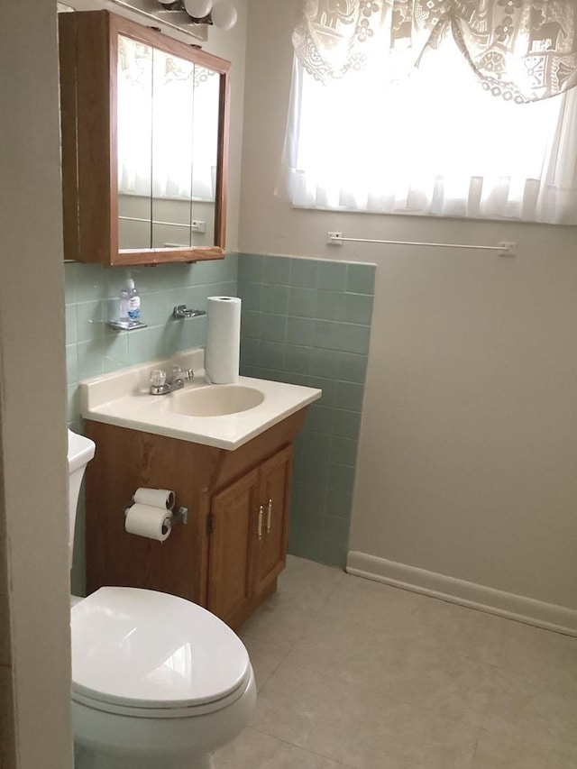 half bath featuring tile walls, toilet, tile patterned flooring, and vanity
