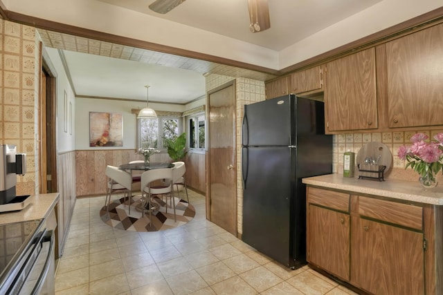 kitchen featuring range, wainscoting, light countertops, freestanding refrigerator, and light tile patterned flooring