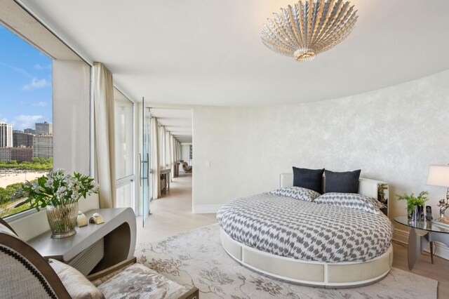 bedroom featuring a view of city, baseboards, and light wood-type flooring