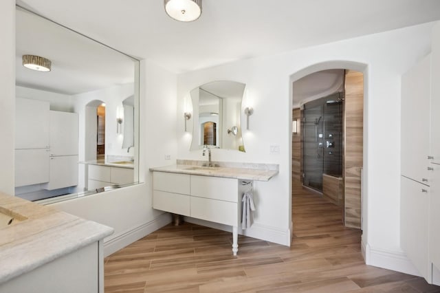 full bath featuring baseboards, walk in shower, wood finished floors, and vanity