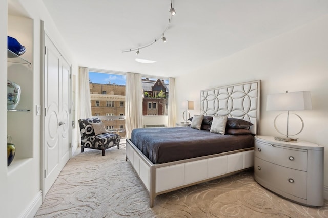bedroom featuring track lighting, floor to ceiling windows, and light colored carpet
