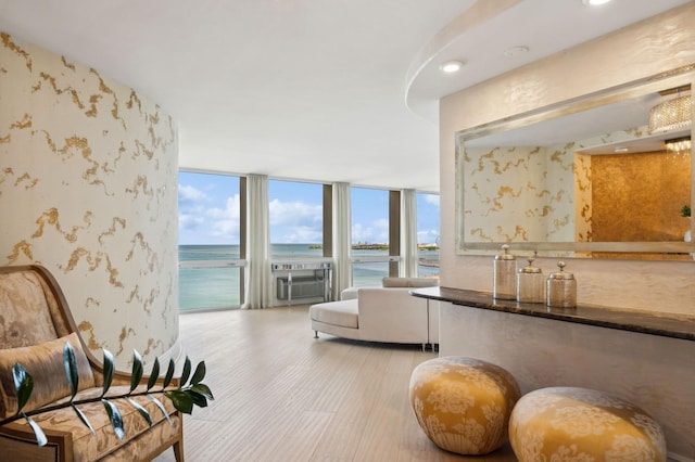 living area featuring a water view, expansive windows, wallpapered walls, cooling unit, and light wood finished floors
