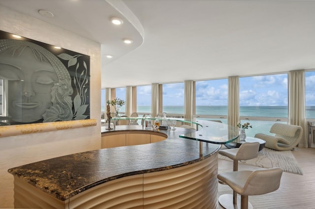 kitchen with dark stone countertops, expansive windows, a water view, and light wood-style flooring