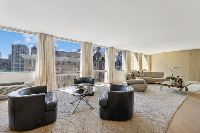 living area featuring wooden walls, an AC wall unit, a view of city, and wood finished floors