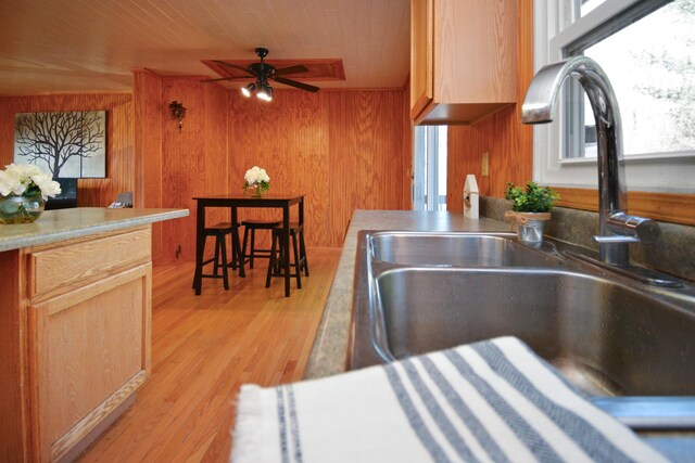kitchen with wooden walls, ceiling fan, a sink, light wood-style floors, and wooden ceiling
