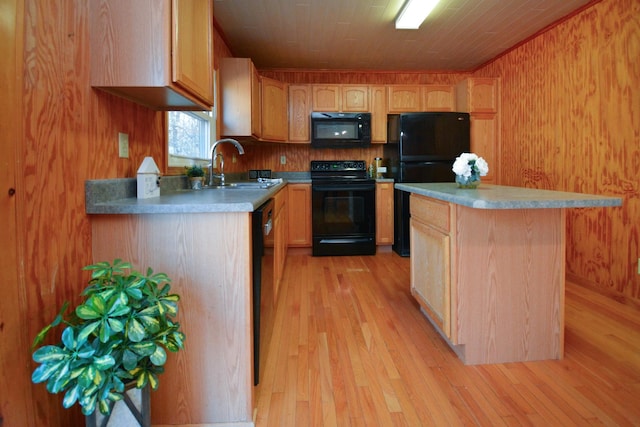 kitchen with light countertops, a center island, a sink, light wood-style flooring, and black appliances