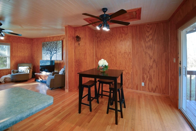 dining space featuring a ceiling fan, wooden ceiling, wood walls, and light wood finished floors