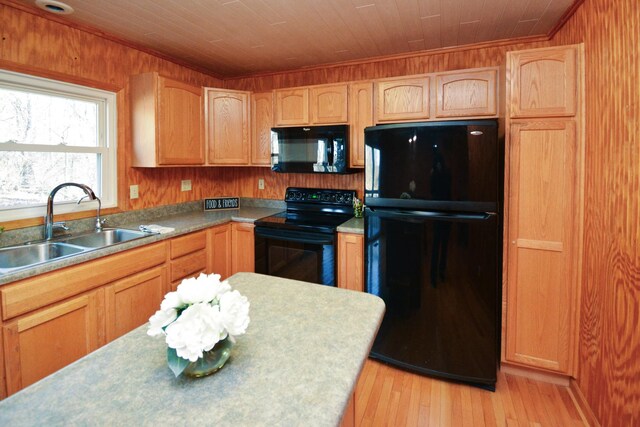 kitchen featuring wooden walls, a sink, light wood-style floors, black appliances, and wood ceiling