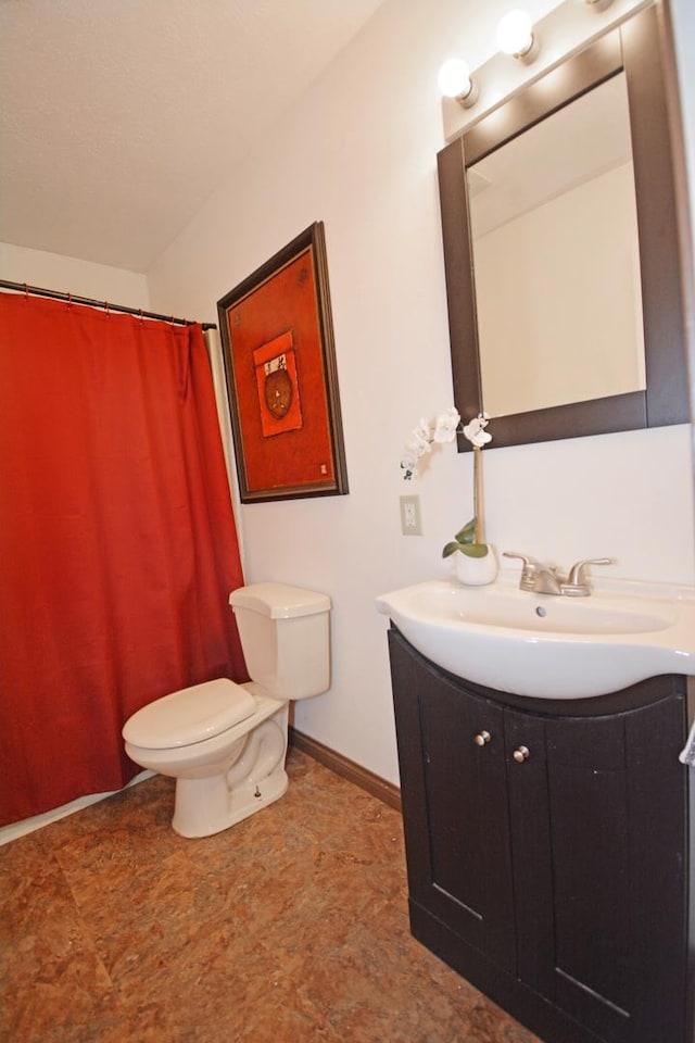 bathroom featuring baseboards, toilet, and vanity