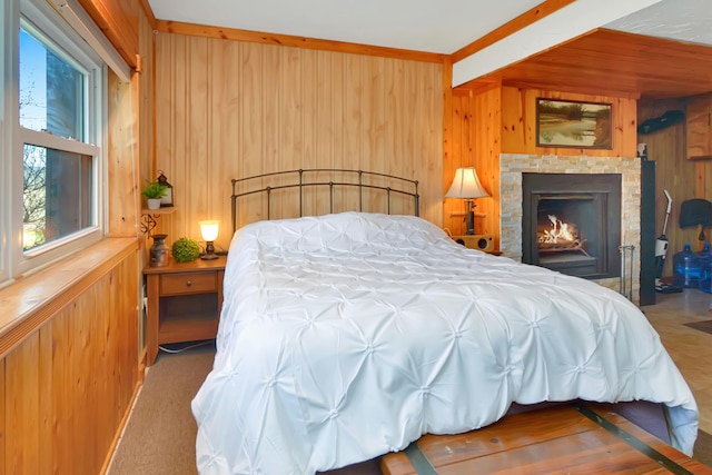 carpeted bedroom with a lit fireplace and wood walls