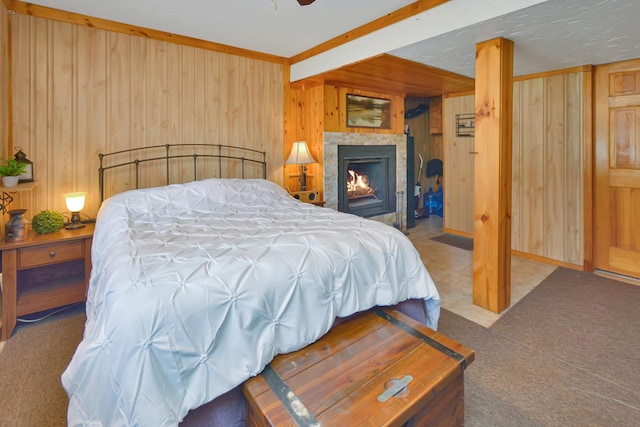 carpeted bedroom featuring a lit fireplace, a ceiling fan, and wooden walls