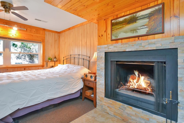 bedroom featuring a warm lit fireplace, visible vents, wooden walls, and wood ceiling