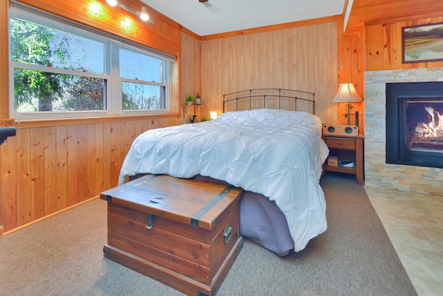 carpeted bedroom featuring wood walls and a lit fireplace