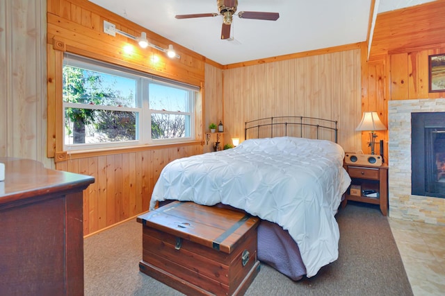 carpeted bedroom featuring a warm lit fireplace, wood walls, and a ceiling fan