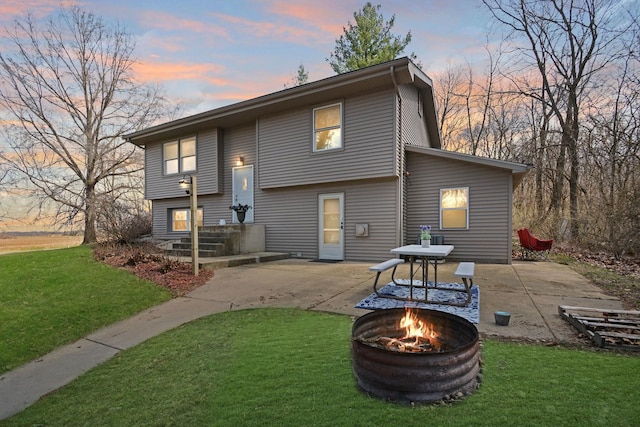 back of property at dusk featuring a patio, an outdoor fire pit, and a yard