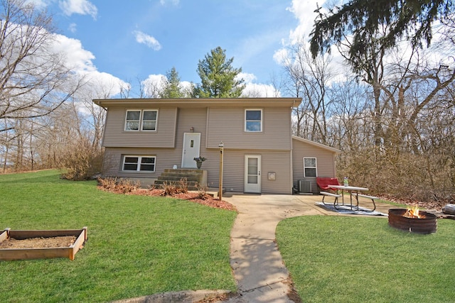 view of front of house with a patio, an outdoor fire pit, a front lawn, and cooling unit