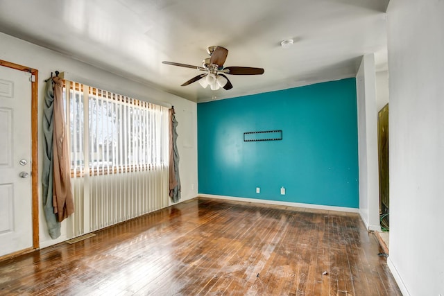 spare room featuring hardwood / wood-style floors, a ceiling fan, and baseboards