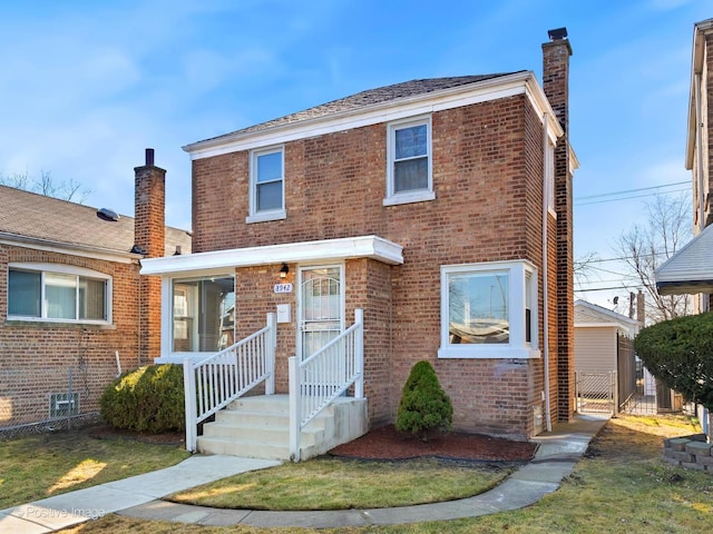 view of front of house featuring a front yard, brick siding, and a chimney