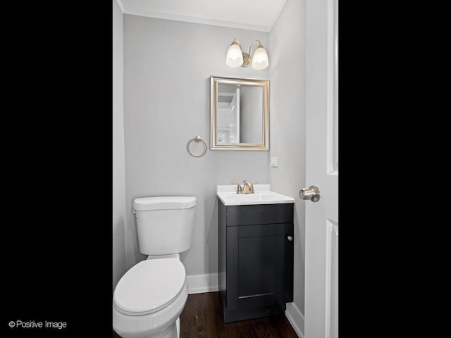 bathroom with vanity, toilet, wood finished floors, and baseboards