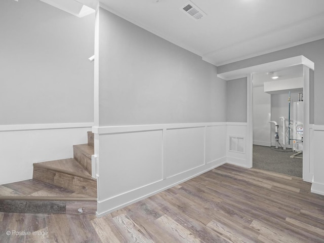 interior space featuring stairs, gas water heater, wood finished floors, and visible vents