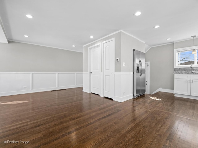 unfurnished living room featuring a sink, dark wood-style floors, recessed lighting, and ornamental molding
