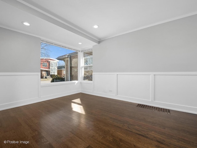 empty room with visible vents, a wainscoted wall, wood finished floors, recessed lighting, and crown molding