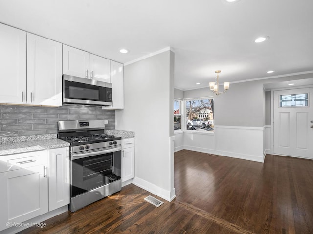 kitchen with visible vents, a chandelier, ornamental molding, light stone counters, and stainless steel appliances