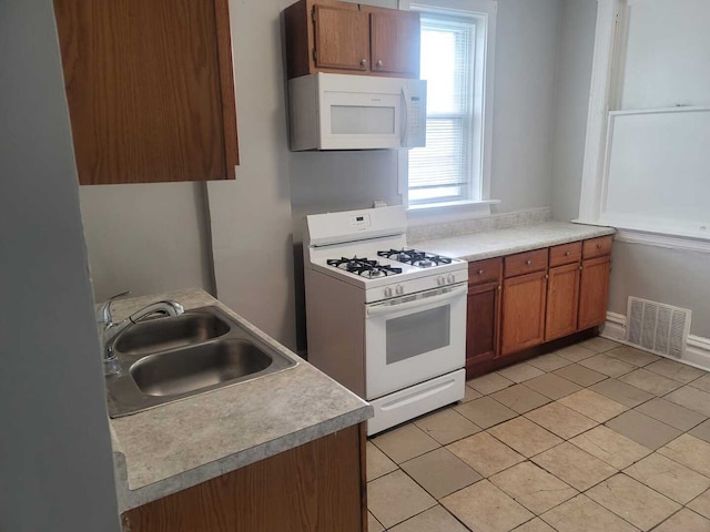 6506 S Eberhart Ave, Chicago, IL 60637 - kitchen featuring a sink, brown cabinets, light tile patterned floors, visible vents, and white appliances