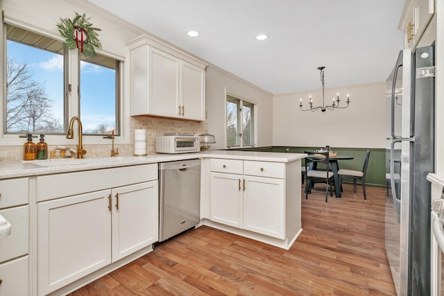 218 San Carlos Rd, Minooka, IL 60447 - kitchen with appliances with stainless steel finishes, a sink, a peninsula, a chandelier, and light countertops