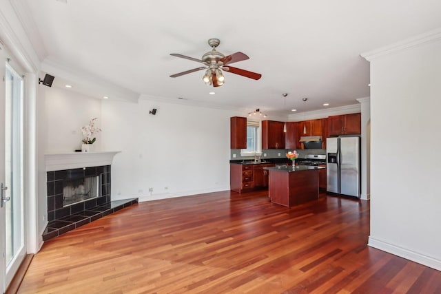 kitchen featuring dark countertops, ceiling fan, under cabinet range hood, open floor plan, and stainless steel refrigerator with ice dispenser