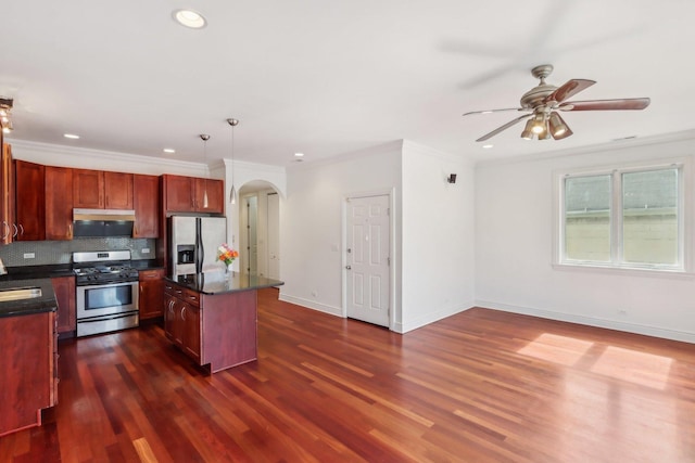 kitchen featuring dark countertops, tasteful backsplash, arched walkways, appliances with stainless steel finishes, and ceiling fan