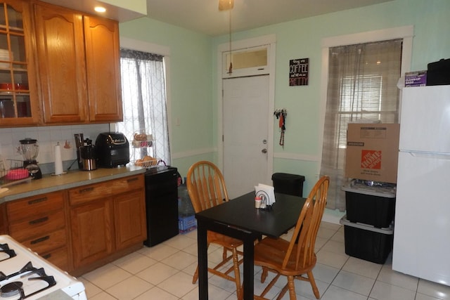 3801 W 46th St, Chicago, IL 60632 - kitchen with brown cabinets, light tile patterned floors, light countertops, freestanding refrigerator, and glass insert cabinets