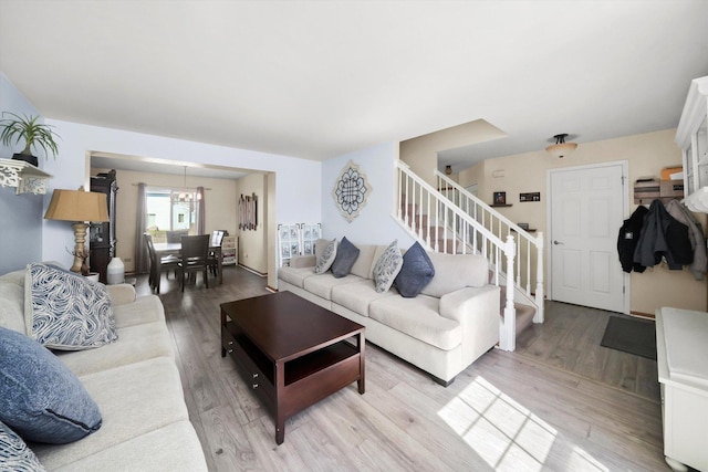 living room with stairway, light wood-type flooring, and an inviting chandelier