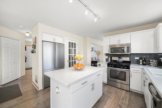 kitchen with tasteful backsplash, light wood-type flooring, light countertops, a kitchen island, and appliances with stainless steel finishes