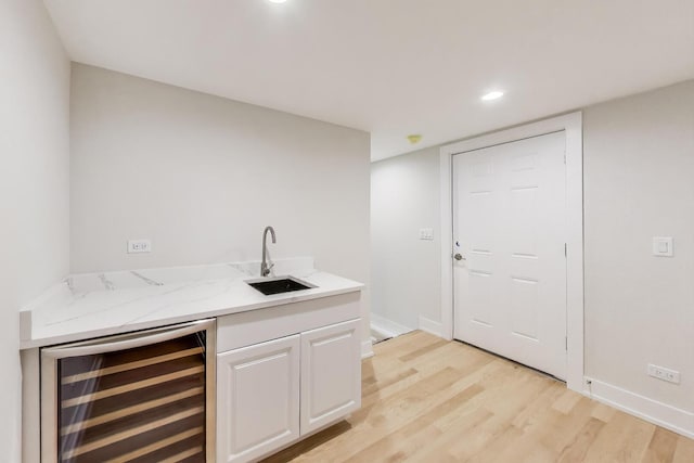 bar featuring a sink, beverage cooler, light wood-style floors, baseboards, and recessed lighting