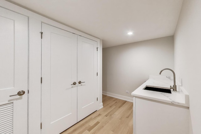 laundry area with recessed lighting, a sink, baseboards, and light wood-style floors