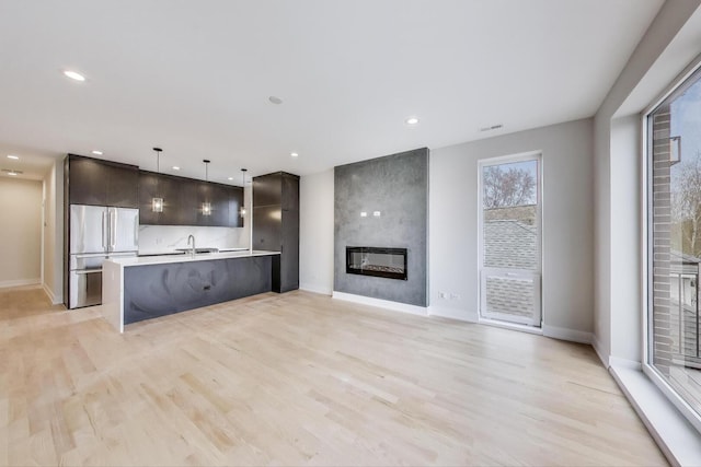 kitchen with light wood finished floors, high quality fridge, light countertops, dark brown cabinets, and modern cabinets