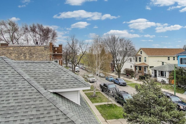 details featuring roof with shingles, a chimney, and a residential view