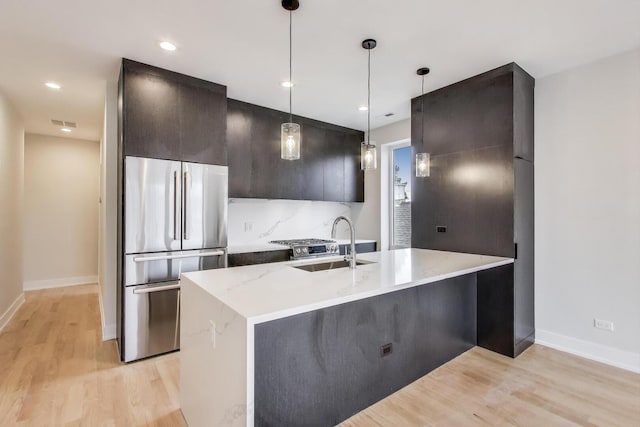 kitchen with a sink, modern cabinets, light wood-style flooring, and freestanding refrigerator