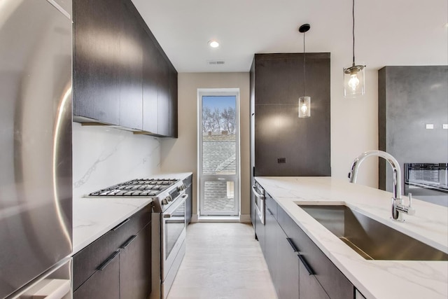 kitchen with modern cabinets, a sink, appliances with stainless steel finishes, and hanging light fixtures