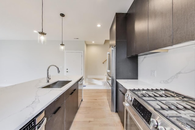kitchen with a sink, modern cabinets, appliances with stainless steel finishes, and light wood-type flooring