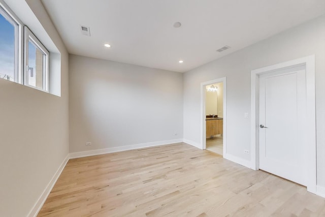 unfurnished bedroom with visible vents, light wood-style flooring, and baseboards