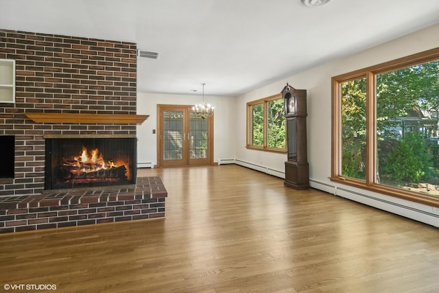 unfurnished living room featuring a chandelier, a fireplace, wood finished floors, and a baseboard radiator