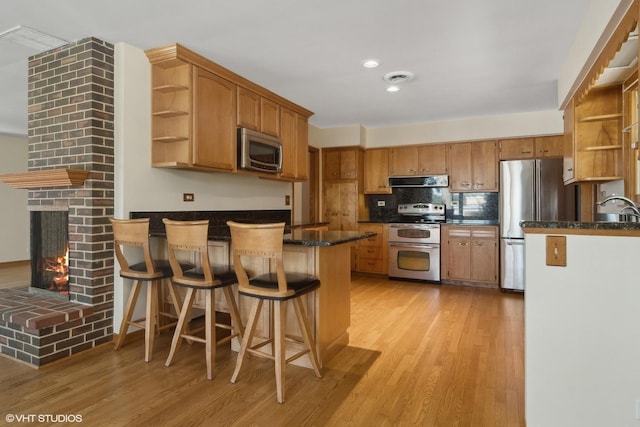 kitchen featuring open shelves, appliances with stainless steel finishes, a peninsula, exhaust hood, and a sink