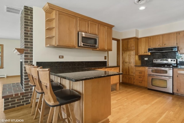 kitchen with light wood-type flooring, visible vents, ventilation hood, stainless steel appliances, and a peninsula