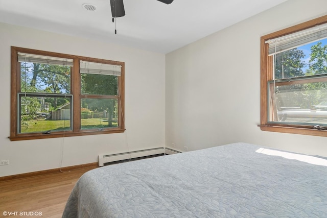 bedroom with visible vents, baseboards, wood finished floors, a ceiling fan, and a baseboard radiator