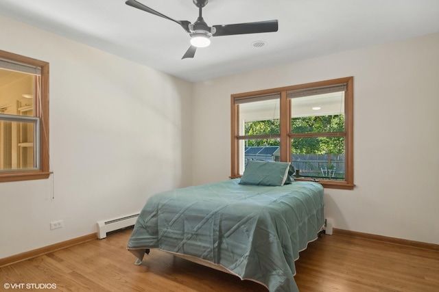 bedroom featuring baseboards, light wood-type flooring, baseboard heating, and ceiling fan
