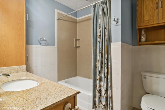 bathroom featuring tile walls, a wainscoted wall, toilet, shower / tub combo with curtain, and vanity